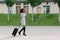 Horizontal view of the cheerful afro-american girl holding the luggage while talking via the mobile phone.