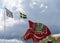 Horizontal view of a colorful Swedish Dala horse and the Swedish flag under an expressive sky