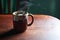 An horizontal view of hot brown cup of ginger tea with steam, tea bag and spoon on rustic wooden table