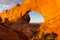 Horizontal view of stunning large red sandstone monument with huge window seen at sunrise in Arches National Park