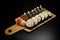 Horizontal view of sushi roll futomaki with avocado and crab meat on wooden serving board on black background.