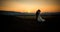 Horizontal wedding shot of the charming newlywed couple kissing at the edge of the mountains during the sunset.