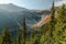 Horizontal wide Photo of lush high mountain altitude massive conifer trees off trail with alpine lake below in the North Cascades