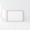 Horizontal Wooden Poster Frame Mockup standing on the white floor in empty room