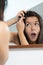 Horrified young woman looking in the mirror