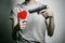 Horror and firearms topic: suicide with a gun in his hand and a red heart on a gray background in the studio
