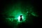 Horror Halloween decorated conceptual image. Alone girl with the light in the forest at night. Silhouette of girl standing between