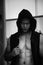 Horror muscular man wear black jacket with hood standing behind the window, black and white picture,