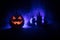 Horror view of Halloween pumpkin with scary smiling face. Head jack lantern with spooky building