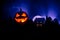 Horror view of Halloween pumpkin with scary smiling face. Head jack lantern with spooky building