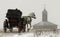 The horse with the carriage moves along the winter road on a background of an old building