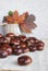 Horse chestnuts or conkers on the table, basket with autumn leaves.