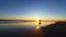 A horse-drawn carriage with a group of people driving at sunset time on the wet and reflecting sand of Parangtritis Beach in middl