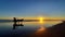 A horse-drawn carriage with a group of people driving at sunset time on the wet and reflecting sand of Parangtritis Beach in middl