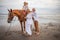 Horse riding on the beach. Two sisters on a horse. Mother leading horse by its rein. Father standing near by. Family concept.