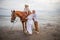 Horse riding on the beach. Two sisters on a horse. Mother leading horse by its rein. Father standing near by. Family concept.