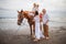 Horse riding on the beach. Two sisters on a horse. Mother leading horse by its rein. Father standing near by. Family concept.