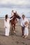 Horse riding. Little pretty girl on a horse. Father leading horse by its rein and talking to daughter. Wife stroking a horse.