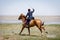 Horseman in blue military clothes riding along the seashore with a sabre in his hand