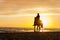 Horseriding at the beach on sunset background. Multicolored outdoors image.