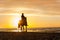 Horseriding at the beach on sunset background. Multicolored outdoors image.