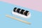 Hosomaki sushi with eel on a white stand on a colorful plain background blue, pink