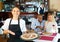 Hospitable latin american waitress meeting guests in pizzeria