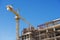 Hospital building under construction with cranes against a blue sky.