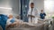 Hospital Ward: Friendly Black Doctor Talks with Elderly Caucasian Patient Resting in Bed, Asks Hea