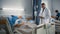 Hospital Ward: Friendly Black Doctor Talks with Elderly Caucasian Patient Resting in Bed. Doctor U