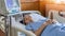 Hospitalized elderly patient senior woman sleeping on bed in hospital ward room with iv medical infusion pump