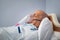 Hospitalized senior patient lying on bed with oxygen mask at hospital
