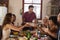 Host and friends pass food round the table at a dinner party