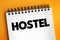 Hostel - low-cost, short-term shared sociable lodging where guests can rent a bed, text concept on notepad