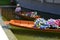 Hostess of the Thailand pavilion of the EXPO Milano 2015 is sitting in a traditional Thai wooden boat filled with heap of flowers.