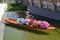 Hostess of the Thailand pavilion of the EXPO Milano 2015 is sitting in a traditional Thai wooden boat filled with heap of flowers.