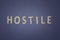 Hostile written with wooden letters on a blue background