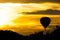 Hot air ballon at sundown over black landscape