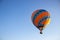 Hot air balloon in clear summer sky. Colorful balloon on blue background. Bright geometric design. Summer adventure and leisure.