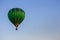 Hot air balloon in clear summer sky. Green balloon on blue background with copy space. Bright geometric design.