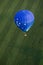 A hot air balloon flies above a farm field