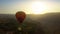 Hot air balloon flying over mountain valley and Armenian village, sunset beauty