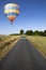 Hot air balloon over single lane country road