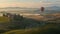 a hot air balloon ride at dawn, as it glides gracefully over a picturesque landscape of rolling hills and vineyards.