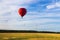 Hot air balloon takes off against the background of the field and forest.  In the background a lot of balloons