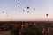 Hot air balloons floating around Burmese pagoda heritage site during sunrise landscape.