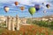 Hot air balloons flying over a field of poppies and rock landscape in Love valley at Cappadocia
