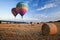 Hot air balloons over hay bales sunset landscape