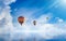 Hot air balloons rising above serene sea, light from heaven, white clouds reflected in water