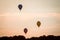 Hot air balloons rising on the horizon at sunset